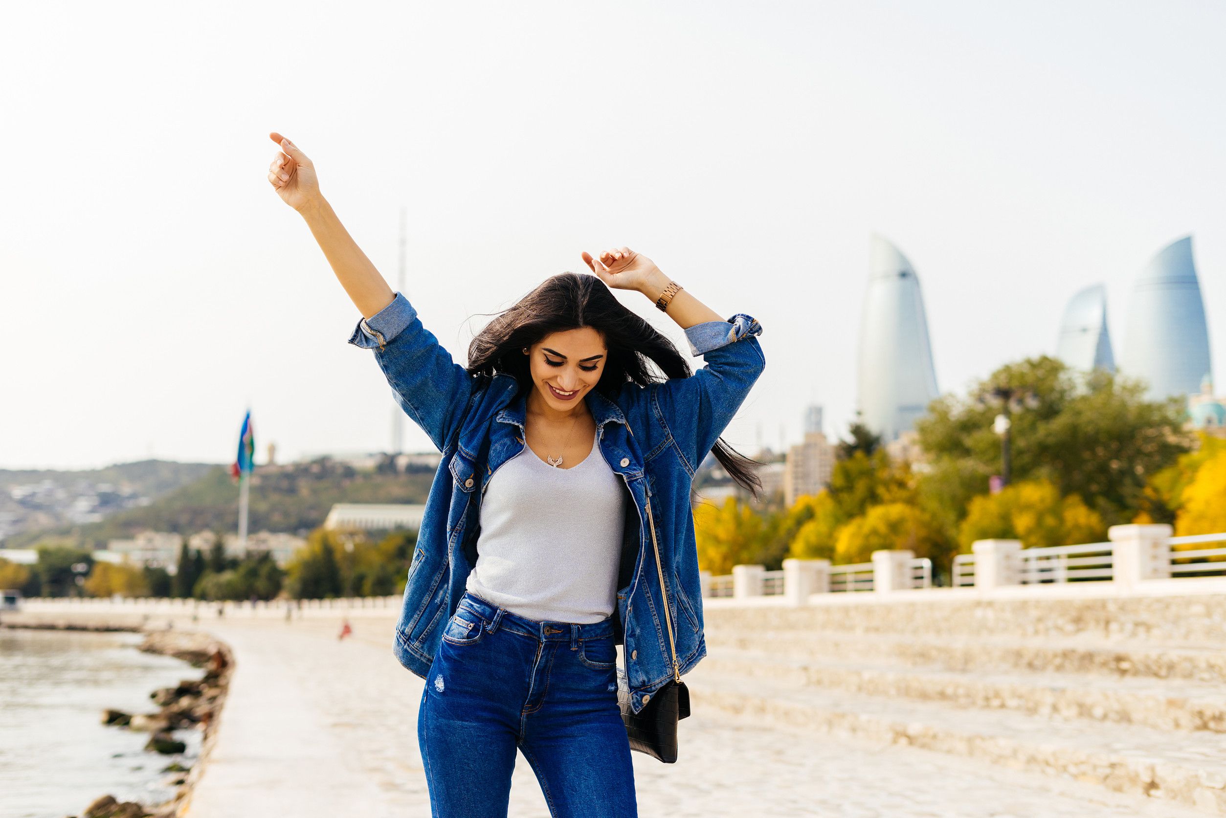 Mujer feliz con una chaqueta vaquera caminando por la ciudad