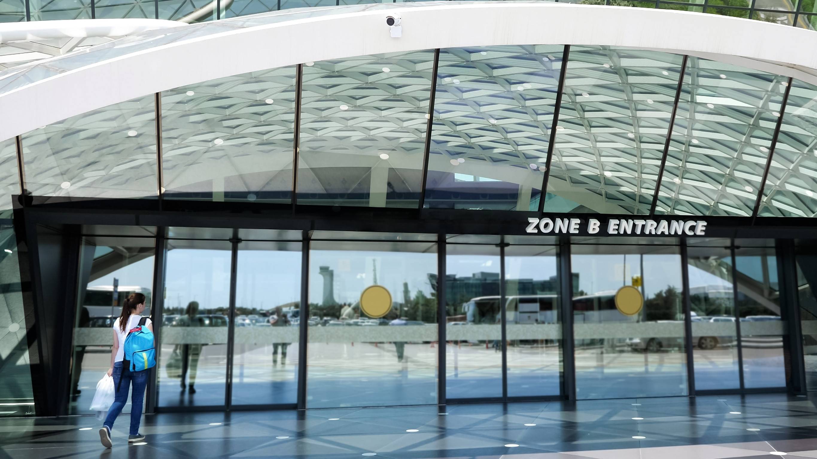 Vista a la entrada del aeropuerto con una mujer entrando por la puerta de la nueva y moderna terminal del aeropuerto.